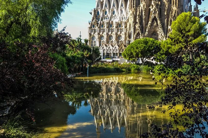The basilica's carved facade reflected in a pond among trees