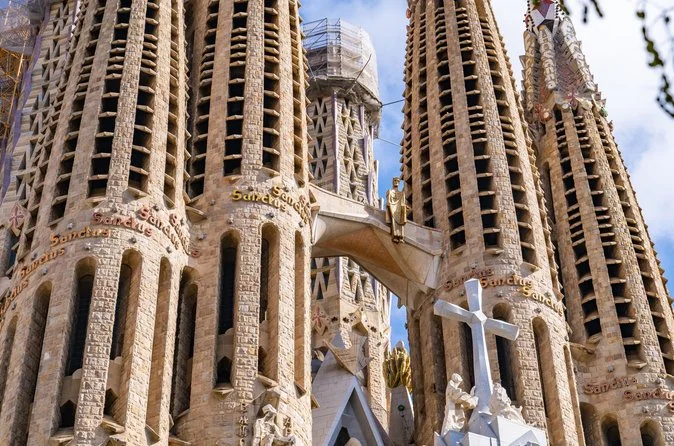Nahaufnahme der Turmspitzen der Sagrada Familia mit eingemeißelter Schrift und einem weißen Kreuz