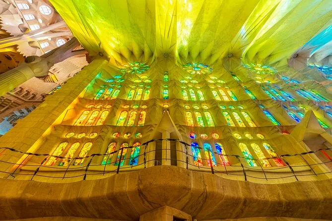 Looking up at walls of yellow and green stained glass above a gallery